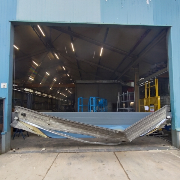 Zwaar beschadigde industriële poort na aanrijdschade klaar voor spoedreparatie